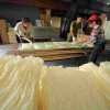 Sun-dried rice noodles are removed from shelves, ready to be packaged.